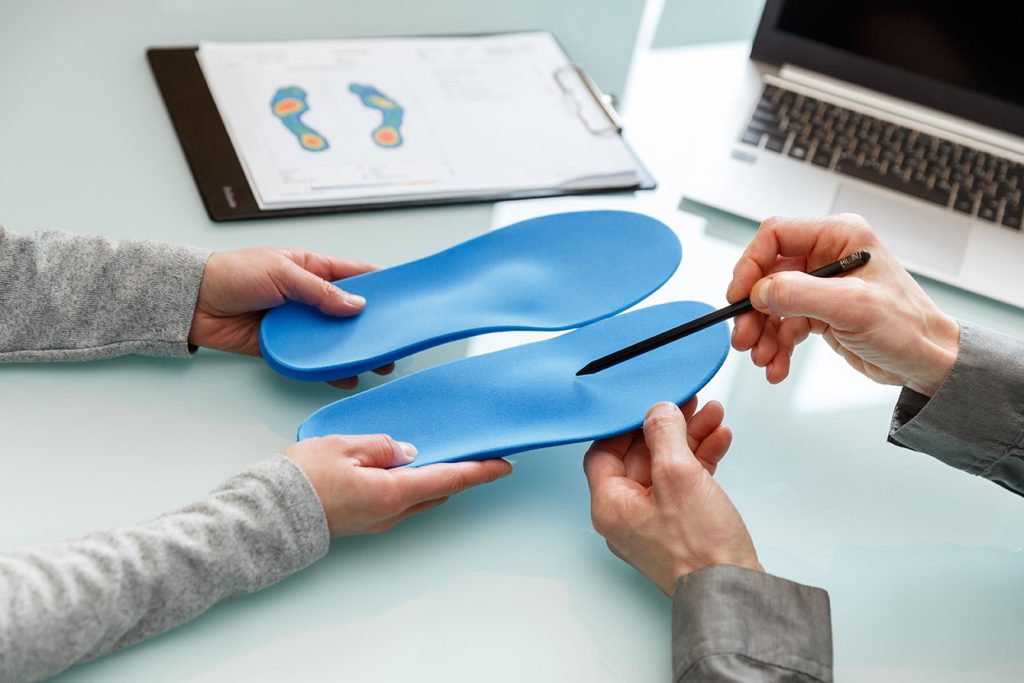 chiropractor showing a patient the features of custom orthotics