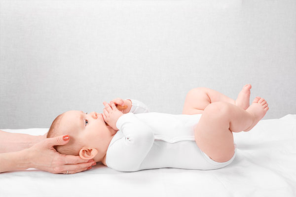 baby is laying down comfortably on their back and a chiropractor is providing a safe and effective treatment